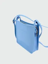 Cartera tipo crossbody de la línea Le Foulonné de Longchamp, confeccionada en cuero granulado de color rojo. Presenta un diseño cuadrado con cierre superior de cremallera y correa ajustable con hebilla metálica.