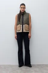 Chaleco acolchado reversible con diseño capitoneado romboidal y cuello alto. Cuenta con cierre frontal de botones a presión.