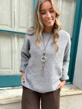 Sweater de punto color gris, de corte holgado, cuello redondo y mangas largas con puños doblados.