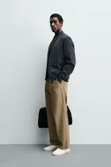 Cazadora bomber ligera de tejido técnico color verde oliva, con cuello, puños y bajo en rib elástico. Presenta cierre frontal de cremallera y bolsillos de vivo en la cadera.