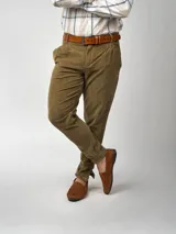 Pantalón de pana negro de corte recto, con bolsillos laterales y traseros. Se ajusta a la cintura con cinturón de cuero negro.