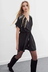 Vestido mini negro con escote cruzado, mangas cortas y cintura elastizada con lazo. Presenta cadenas metálicas en los hombros y en la terminación del lazo.