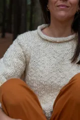 Sweater color crudo de lana merino, con cuello redondo tipo bote y mangas largas abullonadas. Tejido a mano con punto acanalado en puños y ruedo. Corte ajustado al cuerpo.