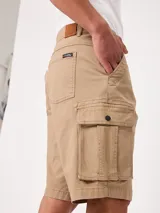 Bermuda cargo de gabardina color beige, con bolsillos laterales con fuelle en las piernas, bolsillos delanteros tipo ojal y traseros. Cuenta con presillas para cinto y cierre frontal con botón y cierre.