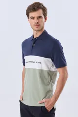Remera polo de manga corta con diseño en bloques de color en tonos azul marino, blanco y verde militar, con bordado frontal y cierre de botones.