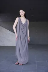 Vestido largo sin mangas con escote drapeado en cascada y silueta suelta de caída liviana.