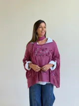 Sweater de punto magenta con diseño holgado, cuello redondo y detalles de encaje floral aplicado en el frente. Incluye una bufanda tipo choker integrada del mismo tejido.