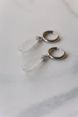 Aros colgantes de acero quirúrgico plateado con dije de piedra natural rosa en forma de lágrima.