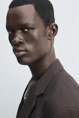 Blazer de corte regular fit confeccionado en tejido con lana. Presenta cuello con solapas de muesca, cierre frontal de un botón, bolsillos de vivo en el pecho y en la cadera, y aberturas en la espalda.