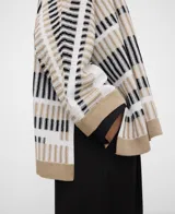 Cardigan tipo kimono confeccionado en punto jacquard con diseño de rayas irregulares en blanco, negro y beige, con mangas japonesas, aberturas laterales y remates en contraste.