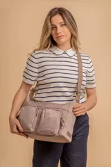 Bandolera de tafeta impermeable color beige, con dos bolsillos frontales con cierre y correa regulable. Diseño práctico y liviano ideal para uso diario.