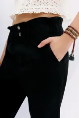 Pantalón blanco de tiro alto con elástico interno en la cintura, botones falsos y terminación con volado. Tiene bolsillos aplicados en delantero y falsos en espalda.