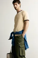 Camiseta regular fit gris melange con cuello redondo y mangas cortas. Presenta acabados con rib en contraste de color marrón oscuro en el cuello y los puños.