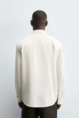 Camisa de corte regular fit confeccionada en tejido de algodón con textura de cuadrillé. Presenta cuello solapa, manga larga con puños abotonados y cierre frontal mediante botonadura.