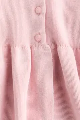 Saco ajustado en punto fino suave, color rosado, con cuello redondo, manga corta, hilera de botones al frente y peplum acampanado.