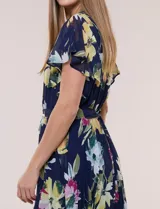 Vestido midi azul marino con estampado floral multicolor, confeccionado en gasa liviana con falda plisada. Tiene escote en V, mangas cortas estilo mariposa y lazo ajustable en la cintura.