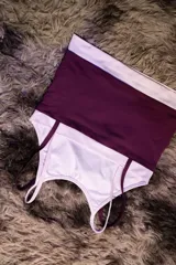 Top deportivo ajustado color morado oscuro con doble capa de tela y tirantes finos blancos. Presenta un logo manuscrito en tono rosado claro en el pecho.