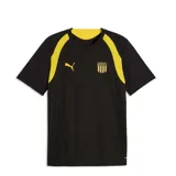 Camiseta de fútbol Puma Cap Tr. Jersey, de color negro con detalles en amarillo en los hombros y cuello. Presenta un sutil diseño gráfico en relieve sobre el tejido y el logo de la marca junto al escudo del Club Atlético Peñarol en el pecho.