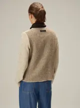 Chaqueta de lana hervida en color beige, con cierre frontal metálico y cuello camisero en contraste de color marrón oscuro. Presenta bolsillos frontales tipo parche y paneles laterales con textura diferenciada.