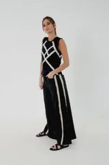 Top de lino 100% color negro con tiras de puntilla de algodón color marfil entrecruzadas formando rombos y puntilla negra en sisas y cuello. Estilo Jackie sin mangas, con cierre de botones en la espalda.