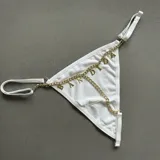 Tanga blanca de tiro bajo con tirantes elásticos regulables y detalle de cadena metálica dorada con dijes colgantes que forman la palabra "Bandida".