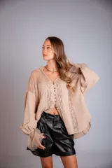 Camisa negra de manga larga con detalles de encaje en hombros y puños. Presenta un cuello tipo solapa y cierre frontal con botones dorados.