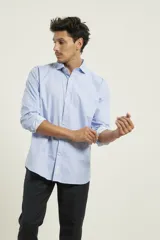 Camisa celeste de vestir, de corte clásico, con cuello abotonado y mangas largas con puños abotonados.