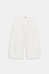 Bermuda larga cargo color blanco, con pinzas delanteras, bolsillos laterales de plastrón con solapa, cierre frontal con cremallera y botón.
