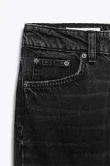 Jeans de tiro alto color negro con efecto lavado, corte mom fit, cinco bolsillos y cierre frontal con cremallera y botón metálico.