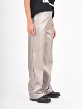 Pantalón de corte recto y tiro medio, confeccionado en cuero sintético negro, con cierre frontal y bolsillos laterales.