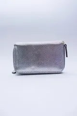 Billetera chica de cuero negro con textura tipo cocodrilo, cierre exterior, bolsillo para monedas con cierre en la parte trasera, múltiples ranuras para tarjetas y billetes, y forro rojo.