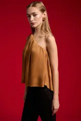 Blusa de poliéster color negro, con diseño asimétrico de un solo hombro, plisado ligero y corte holgado.
