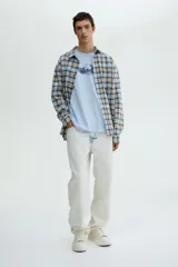 Remera de algodón color celeste con cuello redondo acanalado, mangas cortas y hombros caídos. Presenta un estampado gráfico central con alas y la frase 'No Regret'.