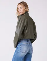 Chaqueta corta de eco cuero color tostado, con cuello alto, cierre frontal con botones a presión y bolsillos de solapa en el pecho. Tiene forro interno a tono.