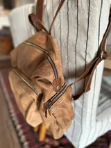 Mochila marrón de cuero con efecto gastado, múltiples bolsillos con cierre y correas ajustables.