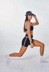 Conjunto deportivo compuesto por un top de breteles finos y un short de tiro alto, ambos en color negro con detalles de ribetes blancos. El top presenta el logo 'bk.' estampado en el frente.