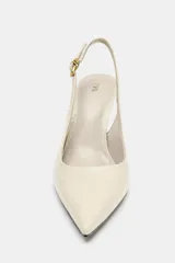 Zapato destalonado de tacón fino con acabado en punta. Presenta una textura con relieve en toda la superficie y una tira trasera ajustable con hebilla metálica.