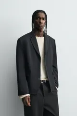 Blazer de corte relajado confeccionada en tejido con mezcla de lana. Presenta cuello con solapas de muesca, cierre frontal de tres botones, bolsillos con solapa en la cadera y un bolsillo en el pecho. Cuenta con manga larga con puños abotonados y aberturas en la espalda.