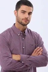 Camisa de manga larga con estampado de cuadros pequeños en tonos rojo, azul y blanco. Presenta cuello abotonado, cierre frontal con botones y un bolsillo pequeño en el pecho.