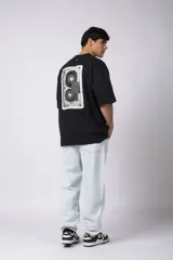 Remera de corte oversize color negro, con cuello redondo y estampa frontal pequeña con la palabra 'REWIND' en color blanco.