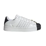 Championes Adidas modelo Superstar II SKTR, de diseño urbano con capellada de cuero blanco, las icónicas tres tiras laterales y la clásica puntera de goma negra. Incluye cordones anchos y detalles metálicos decorativos en el empeine.