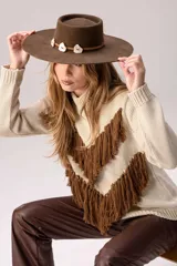 Sweater de punto color crema con cuello medio alto y silueta relajada. Presenta un diseño frontal con líneas en V decoradas con flecos largos de color marrón aplicados a mano.