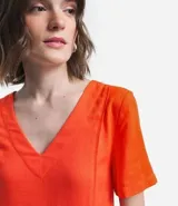 Vestido corto color naranja, de corte recto, con escote en pico y mangas cortas.