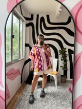 Camisa de manga corta con cuello, diseño estampado abstracto y geométrico en tonos rosados, marrones, amarillos y verdes. Cierre frontal.