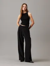 Top sin mangas negro de punto de rayón suave con sutil efecto brillante y bajo asimétrico. Diseño con espalda cruzada y bordado de Calvin Klein en la misma gama de tonos en el bajo.