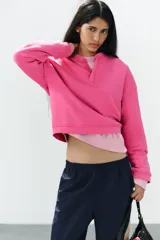 Sudadera fucsia con efecto lavado, confeccionada en mezcla de algodón. Cuenta con cuello redondo con una pequeña abertura frontal con botones, manga larga caída y puños y dobladillo en rib.