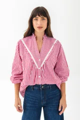 Camisa a rayas verticales rojas y blancas con cuello mao y mangas 3/4 abullonadas. Presenta detalles de puntilla blanca en el canesú. Cierre frontal con botones.