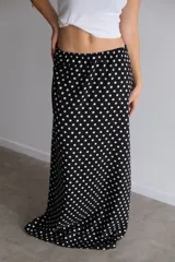 Pollera larga de fibrana color bordó con estampado de lunares blancos, tiro alto y corte amplio.