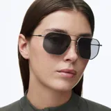 Lentes de sol con montura metálica de acero inoxidable en color gris mate y diseño geométrico inspirado en el estilo aviador. Poseen lentes polarizadas de color negro con protección UV400.