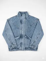 Campera de denim de lavado claro, con cuello alto, cierre frontal oculto bajo solapa y bolsillos diagonales. Presenta costuras decorativas en el frente y hombros, puños y ruedo elásticos.